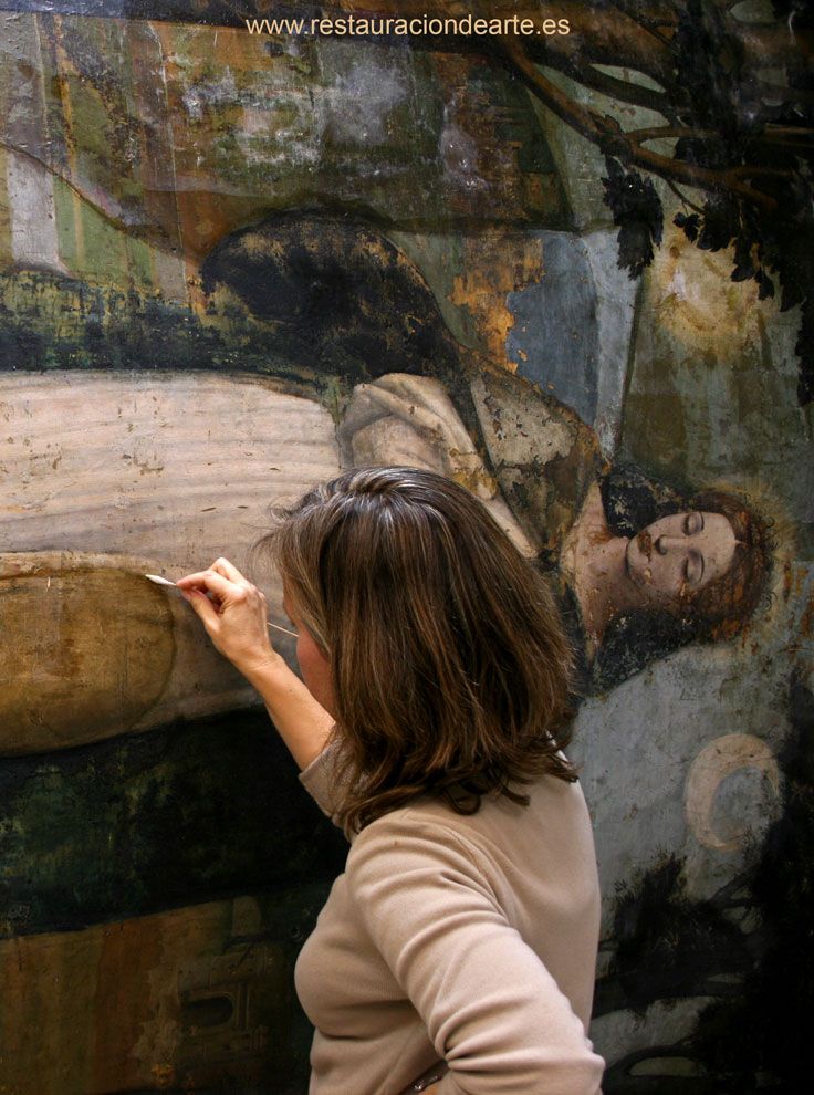 restauradora de pintura sobre tabla en proceso de eliminación de barniz oxidado en el estudio de restauración de Madrid