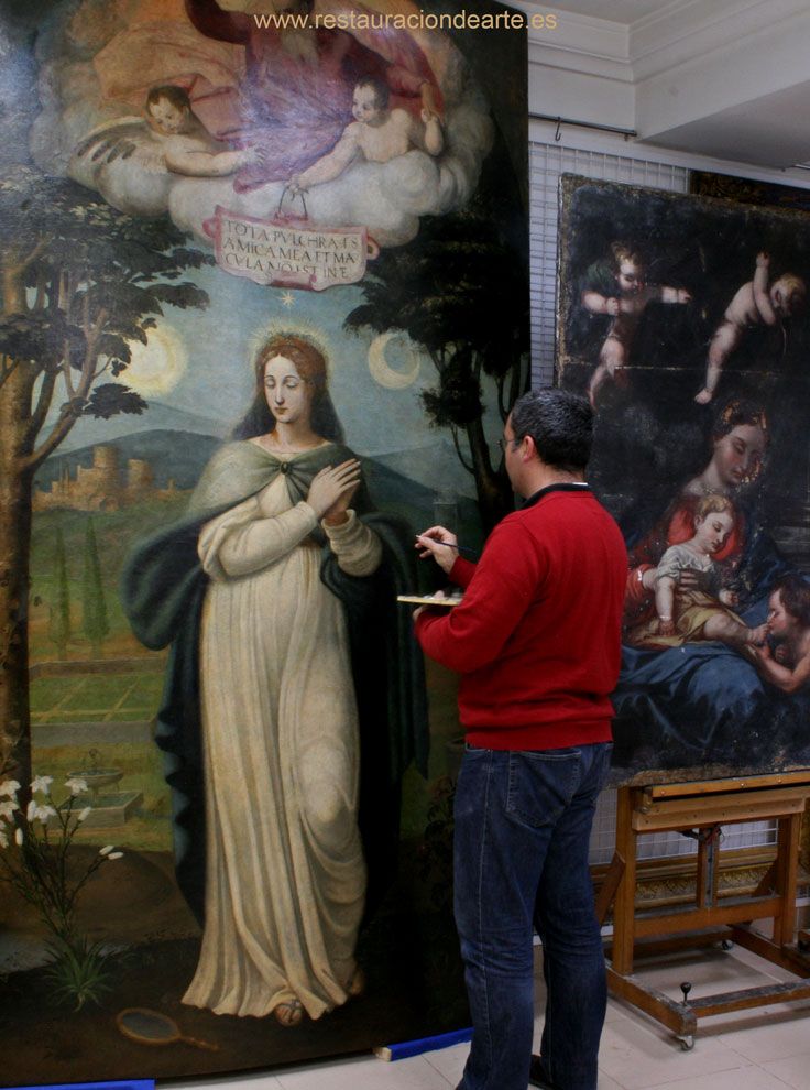 restaurador durante el proceso de reintegración de faltas de pintura en el taller de restauración de pintura sonre tabla en Madrid