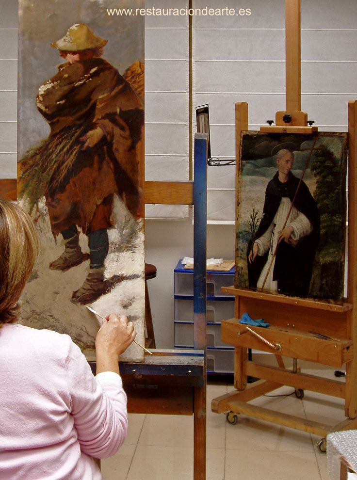 Fotografía de la restauradora en el proceso de la eliminación del barniz oxidado en el estudio de restauración de pintura sobre tabla en Madrid